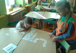 Dziewczynki grają w domino głoskowe.